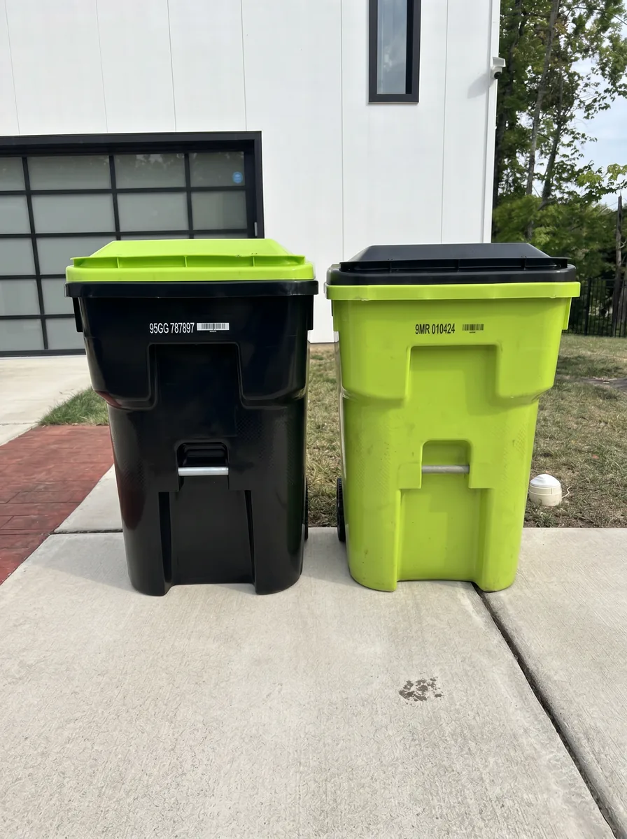Freshly cleaned trash and recycle bins side by side on a driveway