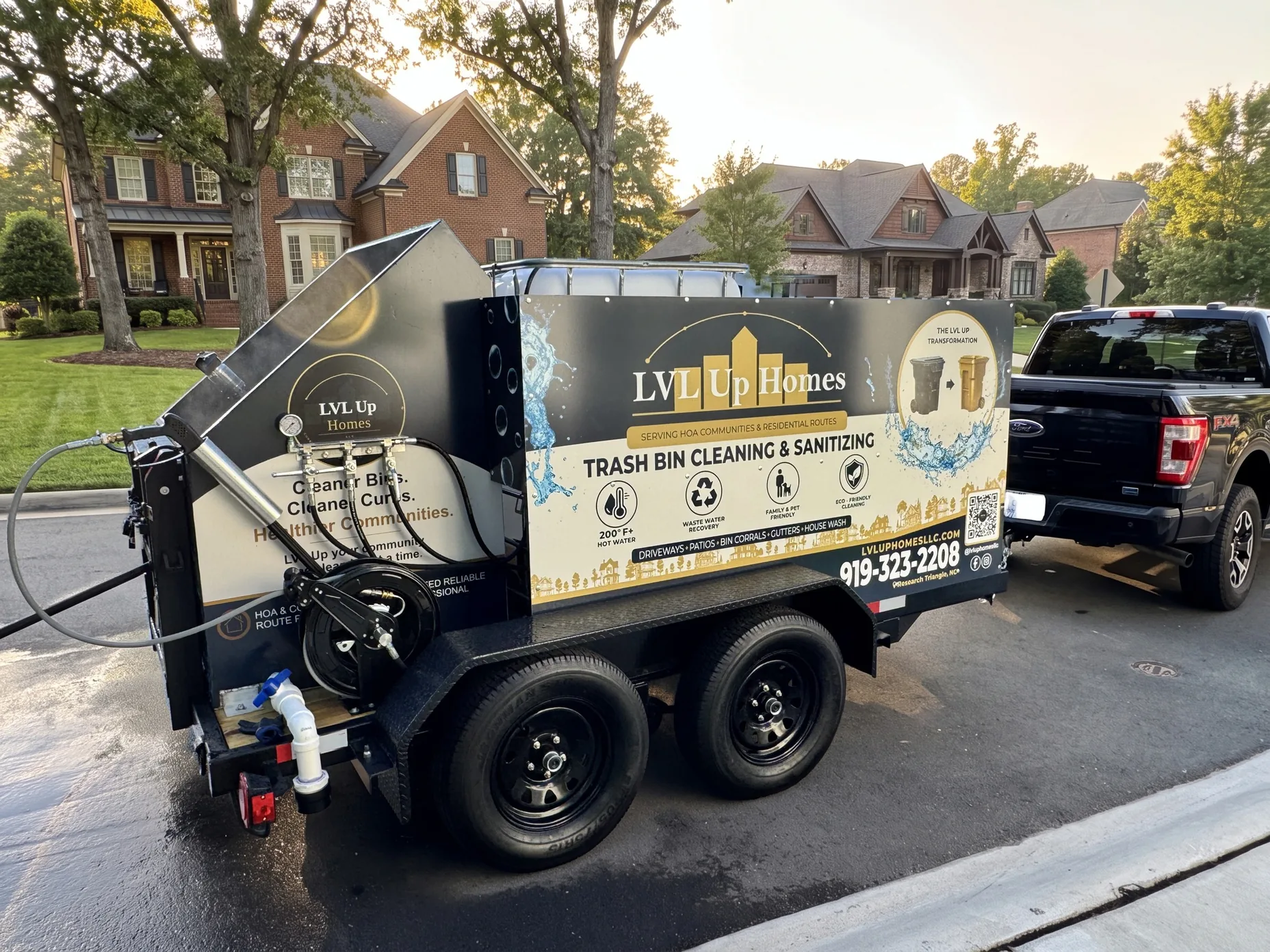 LVL Up Homes truck and bin-cleaning trailer parked curbside in an upscale Triangle neighborhood at golden hour